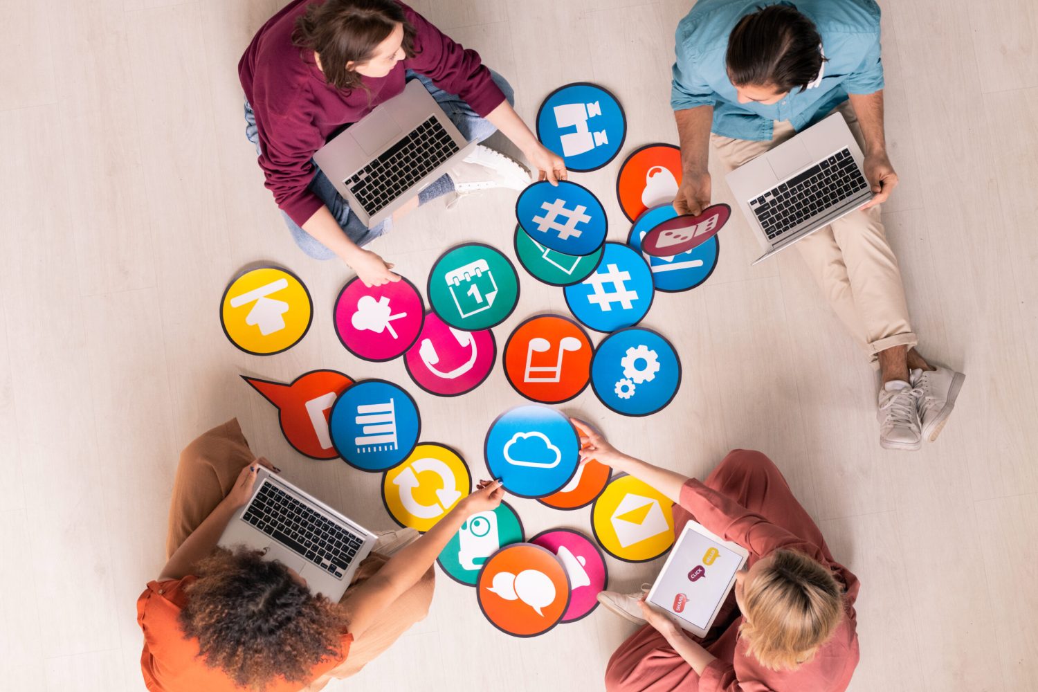 Above view of young social media marketers sitting on floor and using computers while analyzing marketing tools